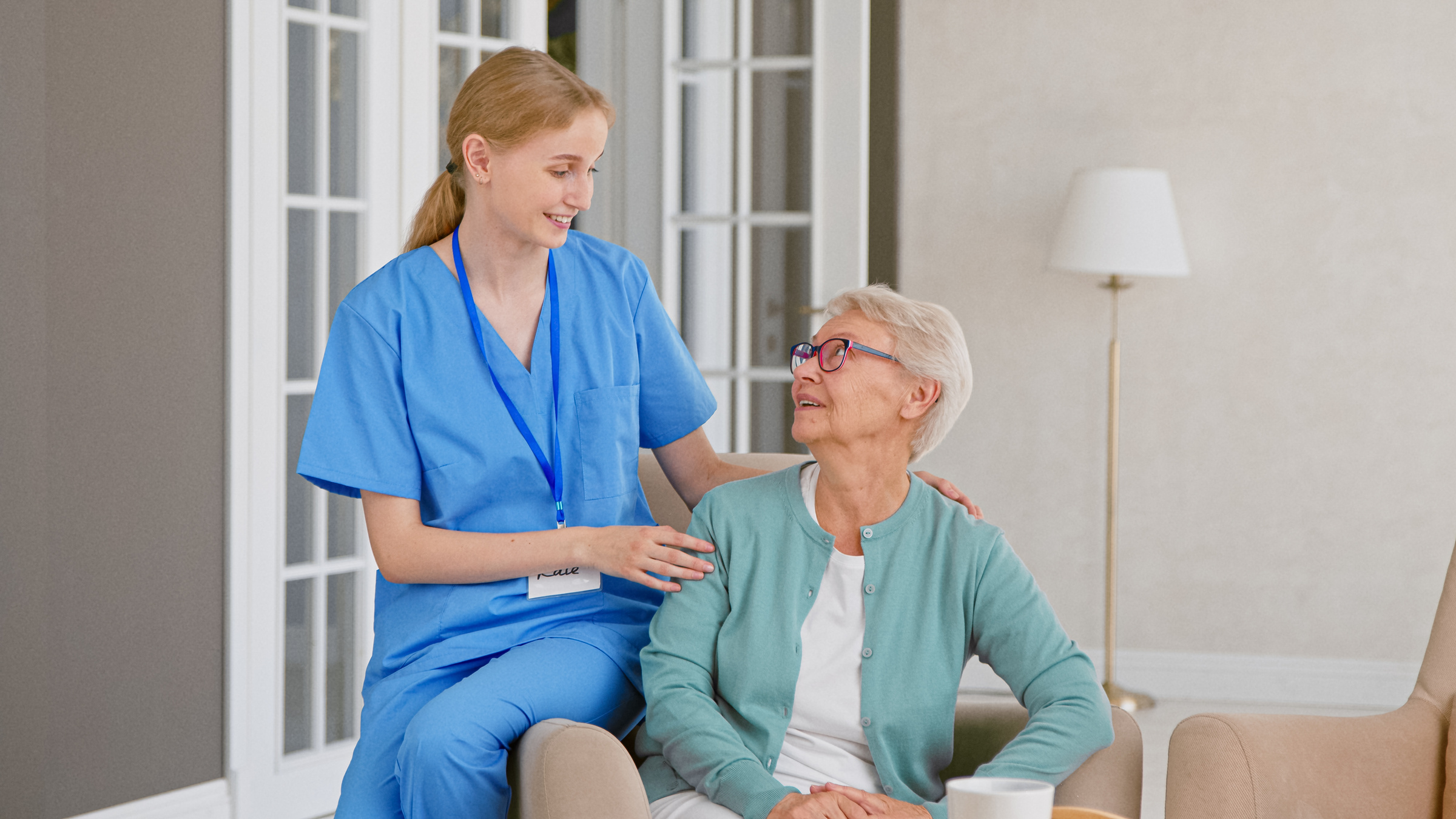 Smiling young blonde nurse in uniform takes care of woman